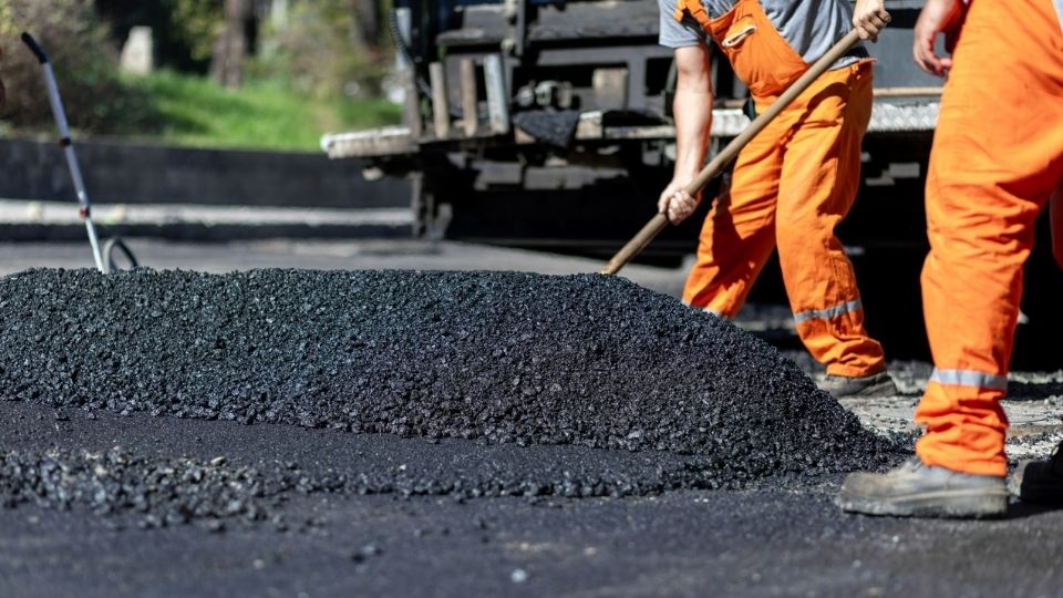 Workers spreading fresh asphalt during commercial driveway resurfacing