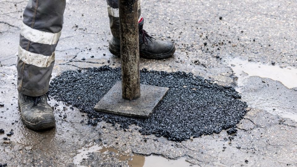 Commercial pothole repair with asphalt patch being compacted
