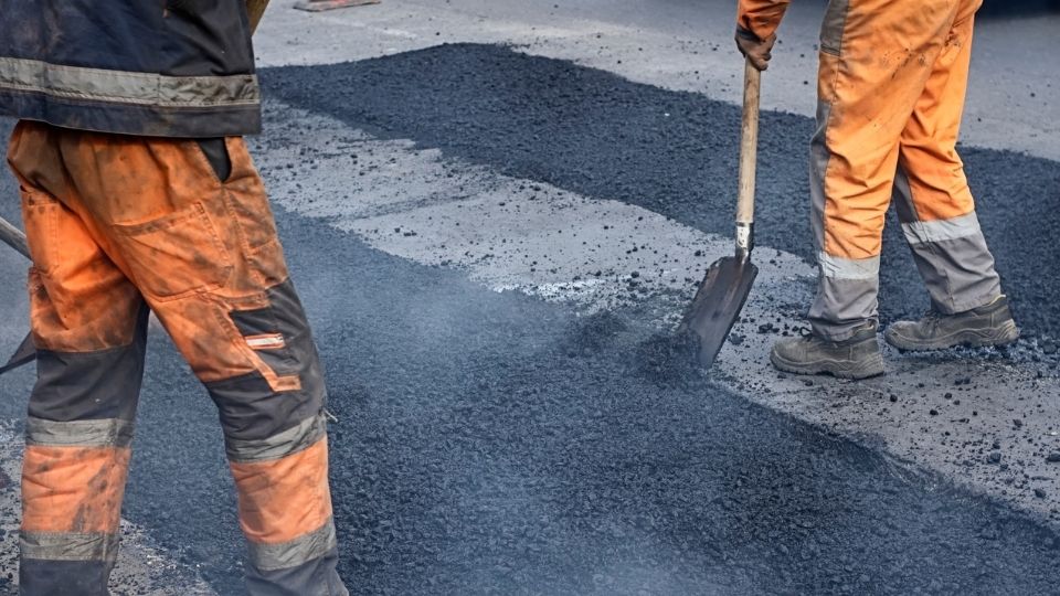 Asphalt patching crew restoring a damaged commercial driveway surface